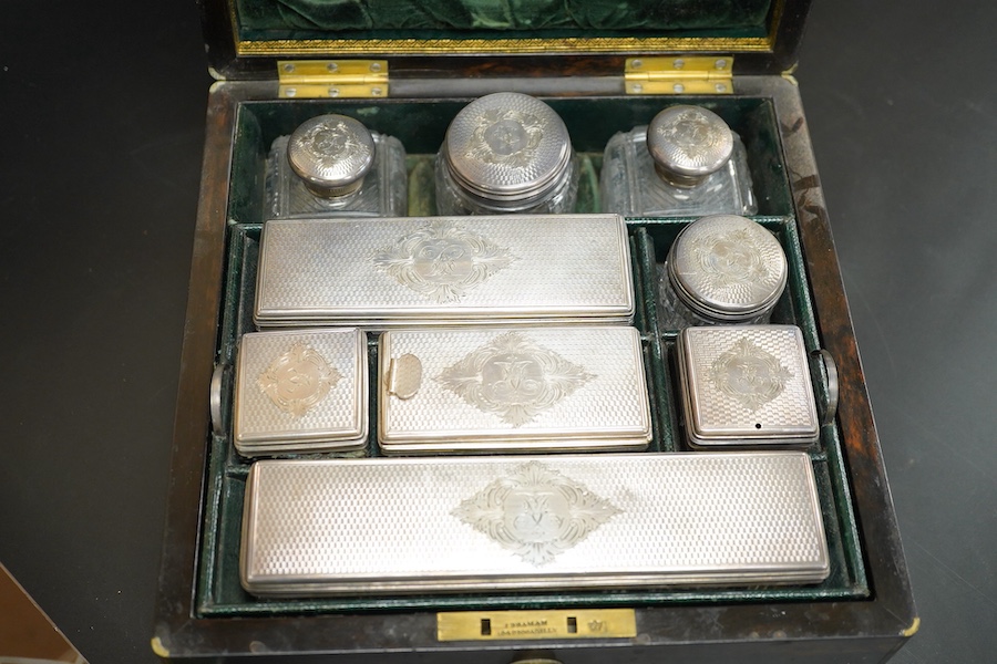 A Victorian brass mounted coromandel wood travelling toilet box, containing nine engine turned silver mounted cut glass toilet jars, with engraved initial, Brownett & Rose, London, 1870, the box of square form, with inse
